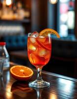 Vibrant orange cocktail garnished with citrus on a wooden bar during evening hours photo