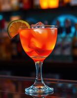 Colorful cocktail served in elegant glass with lemon slice at bar setting during evening hours photo