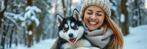 Joyful woman embraces a happy husky in a snow-covered forest during winter photo