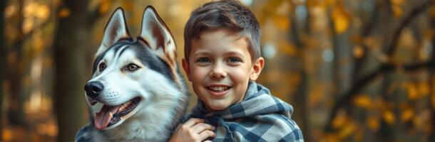 Cheerful boy with a husky dog in a forest during autumn season photo