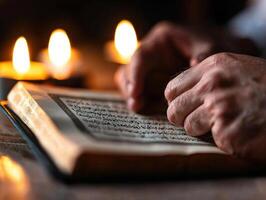 Hands are raised in prayer while reflecting on Quran softly illuminated flickering candlelight. moment captures essence of Islamic devotion during festive occasion photo