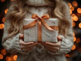 Hands of child are carefully untying ribbon on beautifully wrapped present surrounded soft bokeh lights enhance holiday spirit and atmosphere of celebration photo