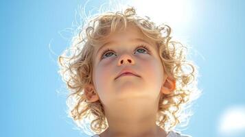 curly blonde haired girl looks up joyful expression amid bright sunlight creating halo effect around her hair capturing moment of pure wonder and innocence photo
