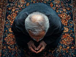 elderly Muslim man kneels in Sujood on richly patterned prayer rug his forehead touching ground as soft golden light filters through nearby windows photo