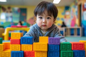In cheerful playroom Asian child focuses on stacking colorful blocks while bright murals create lively atmosphere. Warm indoor lighting adds comfort scene photo