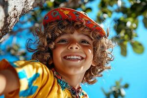 young Hispanic boy climbs sturdy tree in sunny park showcasing big smile while looking down camera. Bright colors enhance lively atmosphere of moment photo