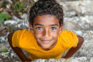Hispanic boy is climbing tree in sunny park while looking down camera bright smile. vibrant colors of his surroundings enhance cheerful atmosphere photo