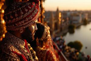 South Asian couple dressed in elaborate traditional attire stands riverbank sunrise. They gaze into distance embodying serenity and cultural richness in beautiful landscape photo
