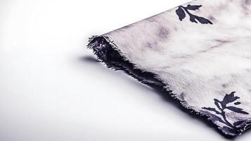 Close-up of a textured fabric with floral patterns draped elegantly on a plain surface photo