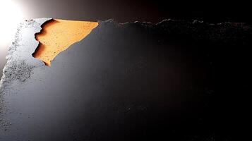 Close-up of a textured surface with peeling black paint revealing an orange underlayer photo