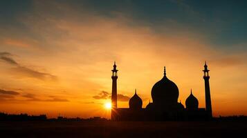 The sun sets behind a mosque in the middle of a field photo
