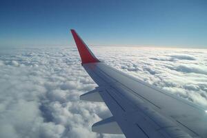 Airplane wing flying above the clouds in a beautiful sunny day photo
