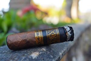 Lit cigar resting on stone surface with blurred background photo