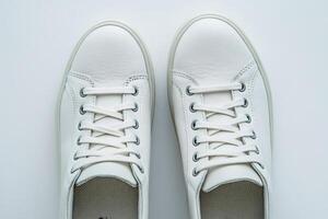 Pair of white leather sneakers with tied laces on white background photo