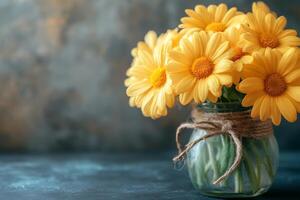 Yellow daisies bouquet in a glass vase with rustic twine on a dark background photo