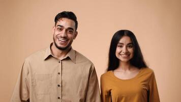 A joyful Arab couple stands side by side in a studio with a light background. Both smile warmly, showcasing their happiness. They share a moment of connection and joy, embodying youthful love. video