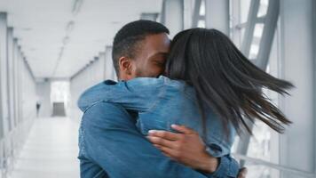 Two African American millennials share a warm embrace at an airport terminal, reflecting joy and connection amidst their travel adventure. The indoor setting evokes a sense of wanderlust. video