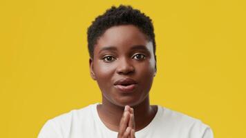 A young African American woman is expressing warmth and positivity in a studio with a vibrant yellow background. Her joyful demeanor highlights her unique beauty and individuality. video