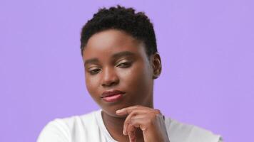 A young African American woman with a chubby build is thoughtfully posing with her hand on her chin. She has a neutral expression and is set against a vibrant, plain backdrop that adds to the focus. video