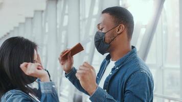Two African American millennials are dancing joyfully indoors at the airport while wearing masks. They exhibit happiness and excitement about their travel adventure amid health concerns. video