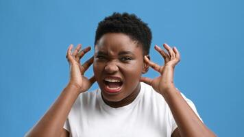 A chubby African American woman is in a studio with a blue background. She appears frustrated, holding her head with both hands and making a facial expression that conveys annoyance. video