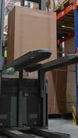 Warehouse employee using a forklift to transport a large box of goods through organized aisles, preparing the shipment for efficient delivery operations video