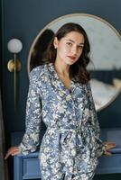 Woman wearing pajamas posing in elegant bedroom with blue walls. photo
