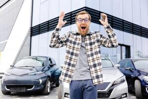 Young man is very impressive and happy, standing in front of his new car photo