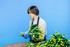 Pensioner lady florist wearing apron, takes care of flowers, working in flower shop photo