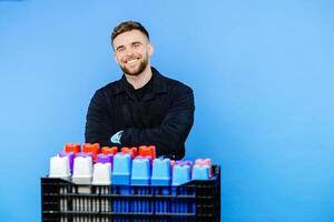 Man holding basket full of small pots for plants on blue background. photo