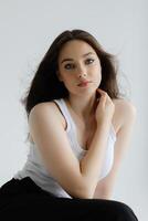 Young woman sitting on stool posing in studio with white background. photo