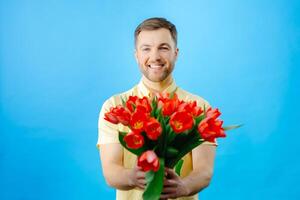 Man holding bouquet of red tulips on blue background. photo