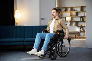 Physical rehabilitation for disabled people. Happy guy in wheelchair making exercises with dumbbell at home. Cheerful impaired young man working out with weights indoors. photo