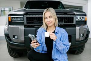Saleswoman drinking coffee and using smartphone in front of pickup truck photo
