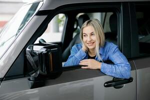 Happy customer smiling while sitting in her new car at the dealership. photo