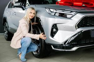 Woman checking new car tires in a dealership. photo