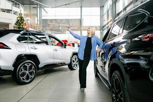 Customer taking selfie with new car in dealership photo
