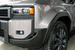 Close-up of front bumper, headlight and wheel of modern gray car photo