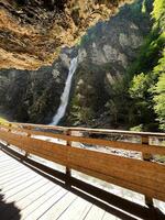Wooden bridge overlooking a scenic waterfall in a lush forested canyon. Liechtensteinklamm, Austria. photo
