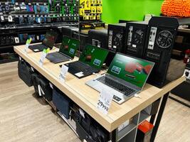 Kyiv, Ukraine - February 04, 2025 Electronics store display with laptops and desktop computers on wooden table photo