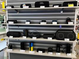 Kyiv, Ukraine - February 04, 2025 Shelf Displaying Assorted Bluetooth Speakers with Prices in an Electronics Store photo