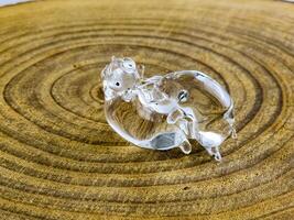 Glass figurine in the form of kissing piglets on a wooden background. Transparent glass photo