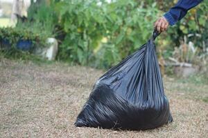 Closeup hand hold black plastic bag that contains garbage inside. Concept , Waste management. Environment problems. Daily chores. Throw away rubbish. Sorting type of garbage. photo