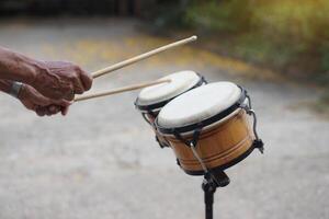 Close up man is beating the bongo drums. Concept, musical percussion instrument for rhythm of music to make more fun for performing or dancing. Beat drum with rhythm along music and songs. photo