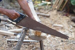 Close up carpenter hand is cutting wood by saw. Concept, tool for cutting. Carpentry , woodwork and construction work tool. Carpentry. use for cutting wood. Handsaw for carpenter. photo