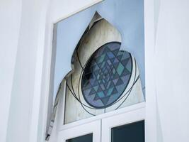 White windows in church with stained glass with various patterns decorating top. photo