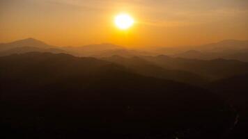 Beautiful sunset in the winter mountains. The setting sun shines down on a serene mountain landscape covered with tropical trees in the. photo
