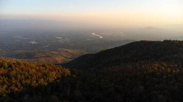 Beautiful sunset in the winter mountains The setting sun shines down on a serene mountain landscape covered with tropical trees in the evening. photo
