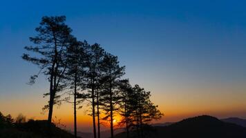 Beautiful sunset in the winter mountains. The setting sun shines down on a serene mountain landscape covered with tropical trees in the evenings. photo