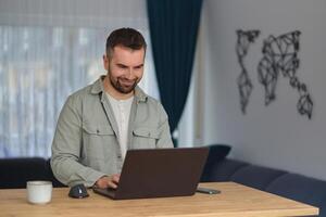 A happy man using a laptop while working at home office. photo
